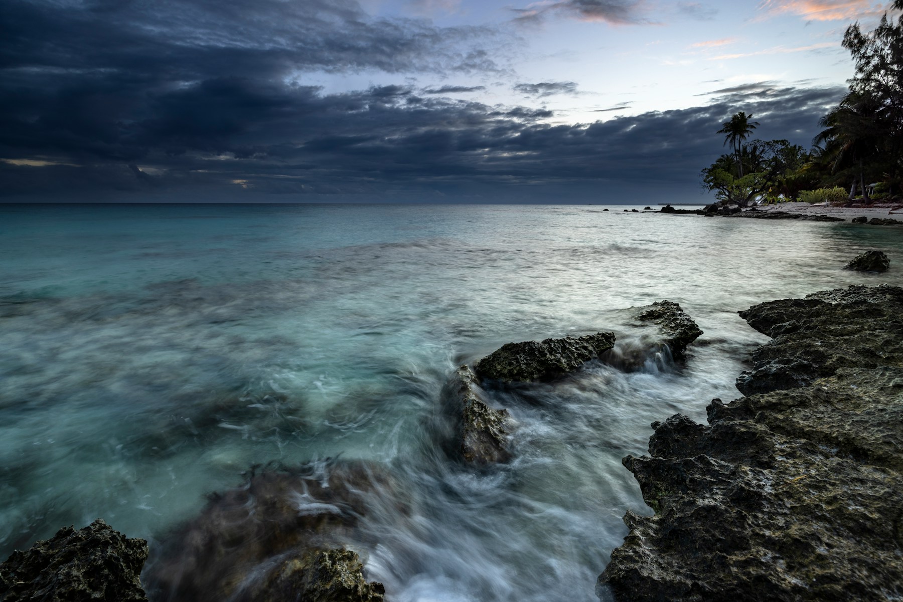 The Pacific meeting Rangiroa’s rocky shore at dusk